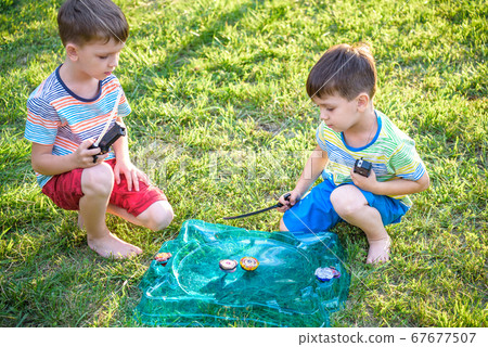 Two boys playing with a spinning top kid toy. Two boys playing with a spinning top kid toy. 67677507