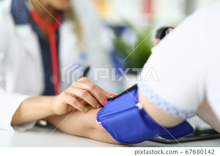 Woman doctor measures pressure to patient in medical office. 67680142