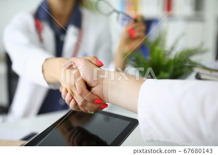 Female doctor shakes hands with her colleague. 67680143