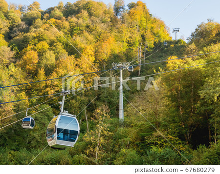 Passenger cabins move along cables of funicular. Cable road at Rosa Khutor Alpine Ski Resort. Sochi, Russia. 67680279