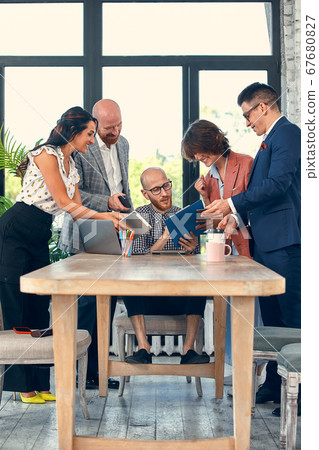 Too many work. Selective focus of young business man surrounded by colleagues, each proposes a project, asks for approval or signing. Deadline 67680827