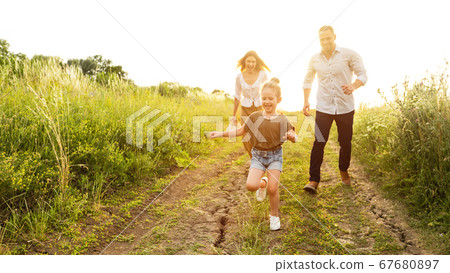 Happy parents and kid running together outdoor in summer 67680897