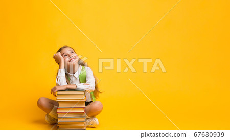 Schoolgirl Dreaming Sitting At Books Stack Over Yellow Background, Panorama Schoolgirl Dreaming Sitting At Books Stack Over Yellow Background, Panorama 67680939