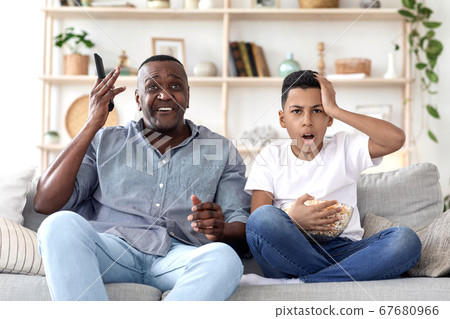 African Grandpa And Grandson Watching Sports On Tv, Emotionally Reacting To Score 67680966