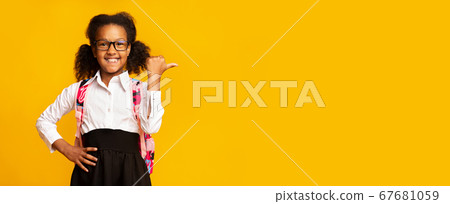 School Girl Pointing Thumb Aside Over Yellow Studio Background, Panorama School Girl Pointing Thumb Aside Over Yellow Studio Background, Panorama 67681059