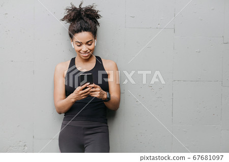Gadgets and devices for sport. Girl with headphones from smart watch looks at smartphone Gadgets and devices for sport. Girl with headphones from smart watch looks at smartphone 67681097