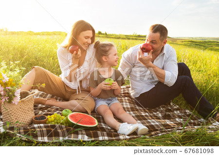 Happy family playing with apples on a picnic outdoors Happy family playing with apples on a picnic outdoors 67681098
