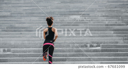 City run. Slim muscular girl in bright athletic uniform runs up the stairs City run. Slim muscular girl in bright athletic uniform runs up the stairs 67681099