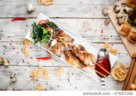 Quail barbecue skewers with salad and red sauce Quail barbecue skewers with salad and red sauce 67683166