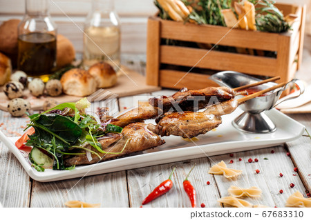 Quail barbecue skewers with salad and red sauce Quail barbecue skewers with salad and red sauce 67683310