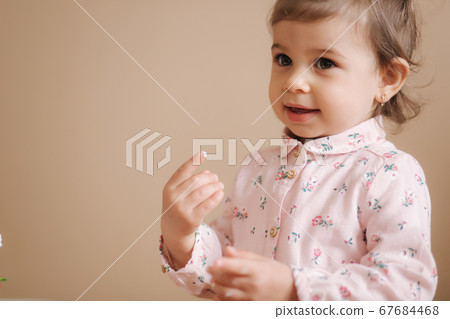 Little girl first time taste bithday cake. Cute little girl in beautiful dress tasting cake with strawberries Little girl first time taste bithday cake. Cute little girl in beautiful dress tasting cake with strawberries 67684468