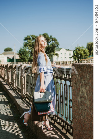 Fashion pretty cool young girl with shopping bags walking on a city street. Young blonde woman enjoying in shopping. Consumerism, shopping, lifestyle concept Fashion pretty cool young girl with shopping bags walking on a city street. Young blonde woman enjoying in shopping. Consumerism, shopping, lifestyle concept 67684553