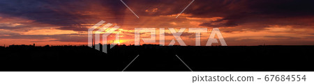 Panoramic view Red bright sunset over the city. City industrial landscape. The rays of the setting sun illuminate the industrial city. 67684554