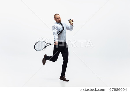 Time for movement. Man in office clothes plays tennis isolated on white studio background. Time for movement. Man in office clothes plays tennis isolated on white studio background. 67686004