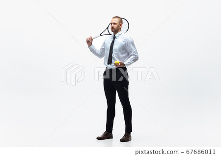 Time for movement. Man in office clothes plays tennis isolated on white studio background. Time for movement. Man in office clothes plays tennis isolated on white studio background. 67686011