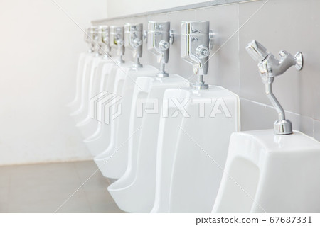 Men's room with white porcelain urinals in line. 67687331