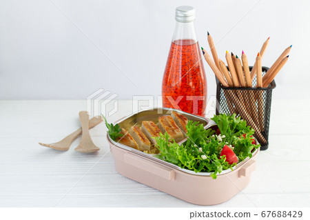 Lunch box with healthy meal and fruit juice for school children on white background next to stationery Lunch box with healthy meal and fruit juice for school children on white background next to stationery 67688429