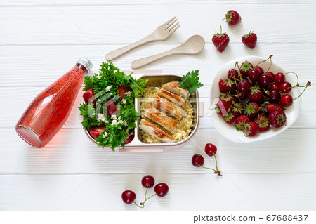 Open lunchbox with chicken, couscous and vegetable salad for school or office take away. Lunch box next to basil seeds drink and fresh berries top view Open lunchbox with chicken, couscous and vegetable salad for school or office take away. Lunch box next to basil seeds drink and fresh berries top view 67688437