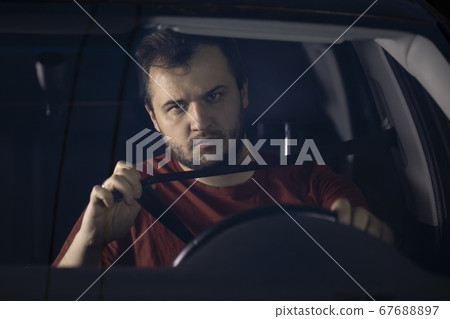 Young bearded man fastens his seat belt in a car. Safe driving Young bearded man fastens his seat belt in a car. Safe driving 67688897