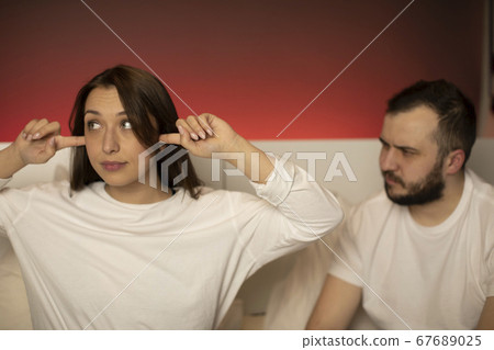 cute brunette girl puts her fingers in ears can't hear what boyfriend saying 67689025