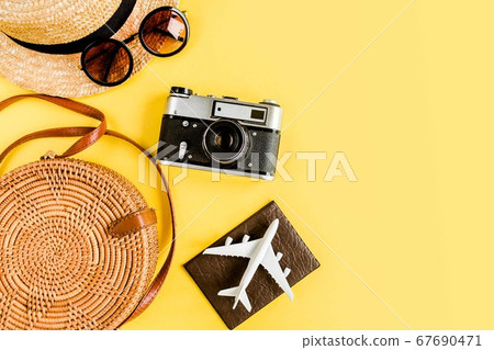Eco rattan bag, retro camera, model plane, airplane and straw hat. Traveler accessories concept on yellow background. 67690471