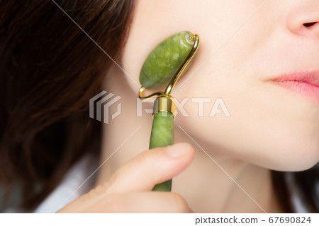 Woman with jade face roller 67690824