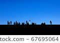 People photographed in silhouette against a blue sky 67695064