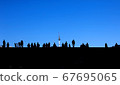 People photographed in silhouette against a blue sky 67695065
