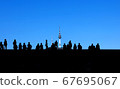 People photographed in silhouette against a blue sky 67695067