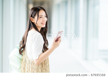 A college student operating a smartphone on campus A college student operating a smartphone on campus 67695388