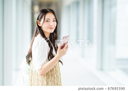 A college student operating a smartphone on campus 67695390