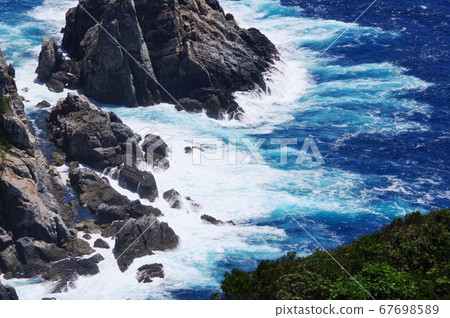 深藍色的大海和潔白的浪花在岩石上 67698589