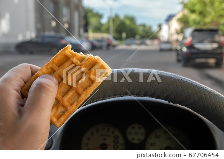 food, cookies in the hand of a car driver while driving in the city food, cookies in the hand of a car driver while driving in the city 67706454
