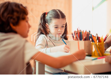 Concentrated girl drawind with color pencils during the art class 67707148