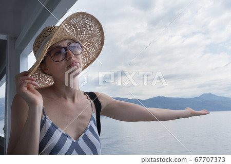 Disappointed female tourist on summer cruss ship vacation, checking if it rains, looking angry at overcast cloudy sky. Allways take the weather with you on summer vacations 67707373