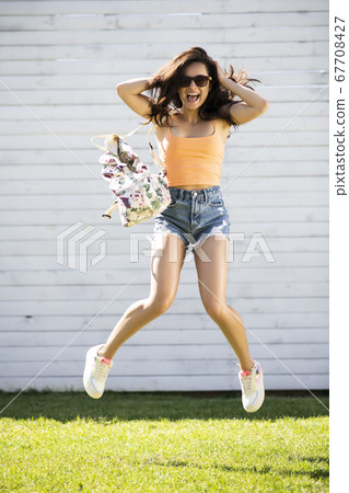 Pretty brunette girl in shorts jumping and smiling 67708427