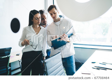 Man writing in notebook while standing in office 67708464