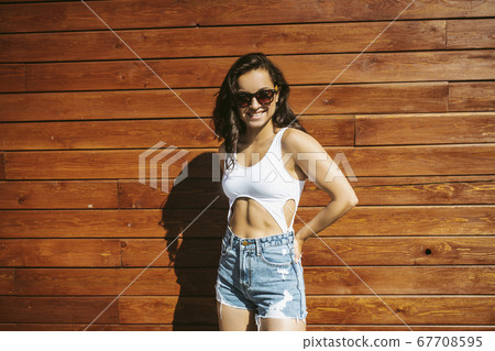 Beautiful brunette girl in shorts standing near the wooden wall 67708595