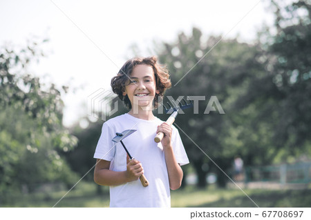 Dark-haired boy holding gardening equipment and smiling Dark-haired boy holding gardening equipment and smiling 67708697