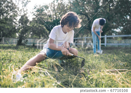 Dark-haired boy and his dad looking busy with gardening Dark-haired boy and his dad looking busy with gardening 67710108