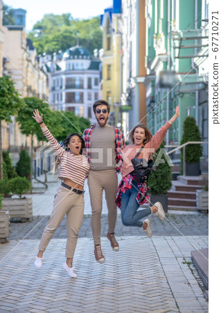 Guy and two girls bouncing up together on the street. Guy and two girls bouncing up together on the street. 67710271