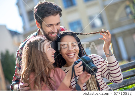 Happy guy and two girls looking at pictures in camera 67710852