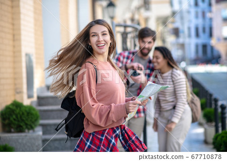 Happy long-haired girl with backpack and map in her hands. Happy long-haired girl with backpack and map in her hands. 67710878
