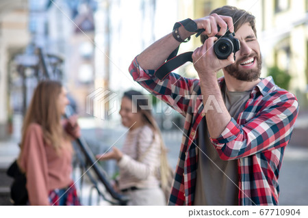 Guy in plaid shirt photographing on camera on street. Guy in plaid shirt photographing on camera on street. 67710904