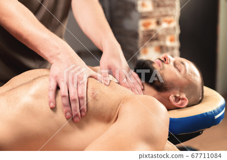 A professional therapist massages the pectoral muscle of an athlete to a man in a professional massage salon. The concept of professional help of a manal therapist A professional therapist massages the pectoral muscle of an athlete to a man in a professional massage salon. The concept of professional help of a manal therapist 67711084