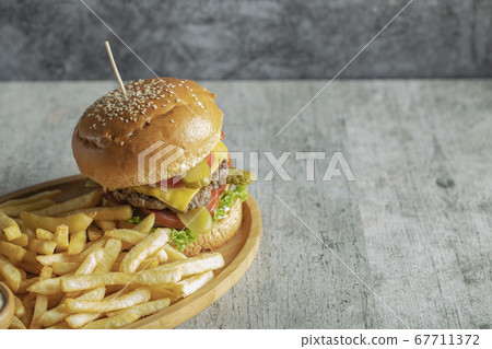 Burger and fried potatoes in a wooden platter Burger and fried potatoes in a wooden platter 67711372