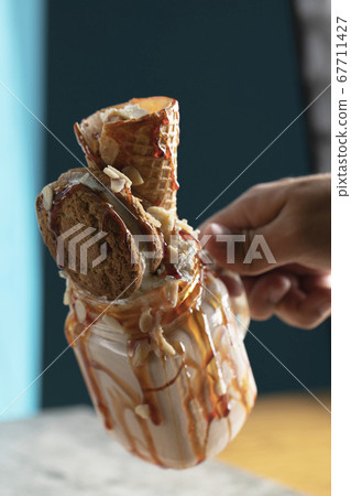 Milky summer cocktail with waffle and mapple syrup in the hand 67711427