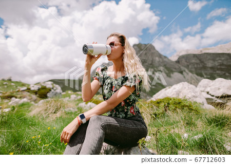 woman drinking coffee with mug and relax in mountains 67712603