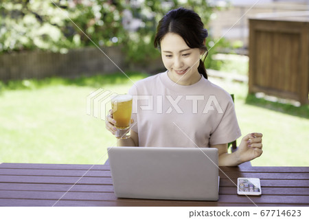 一個年輕的女人在露台上有一個在線的喝酒聚會 67714623