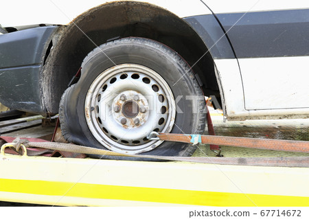 Car is on tow truck with flat tire closeup 67714672